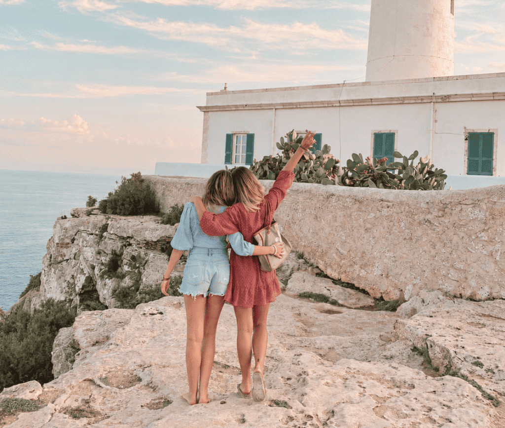 Dos amigas de viaje por la costa en verano abrazándose